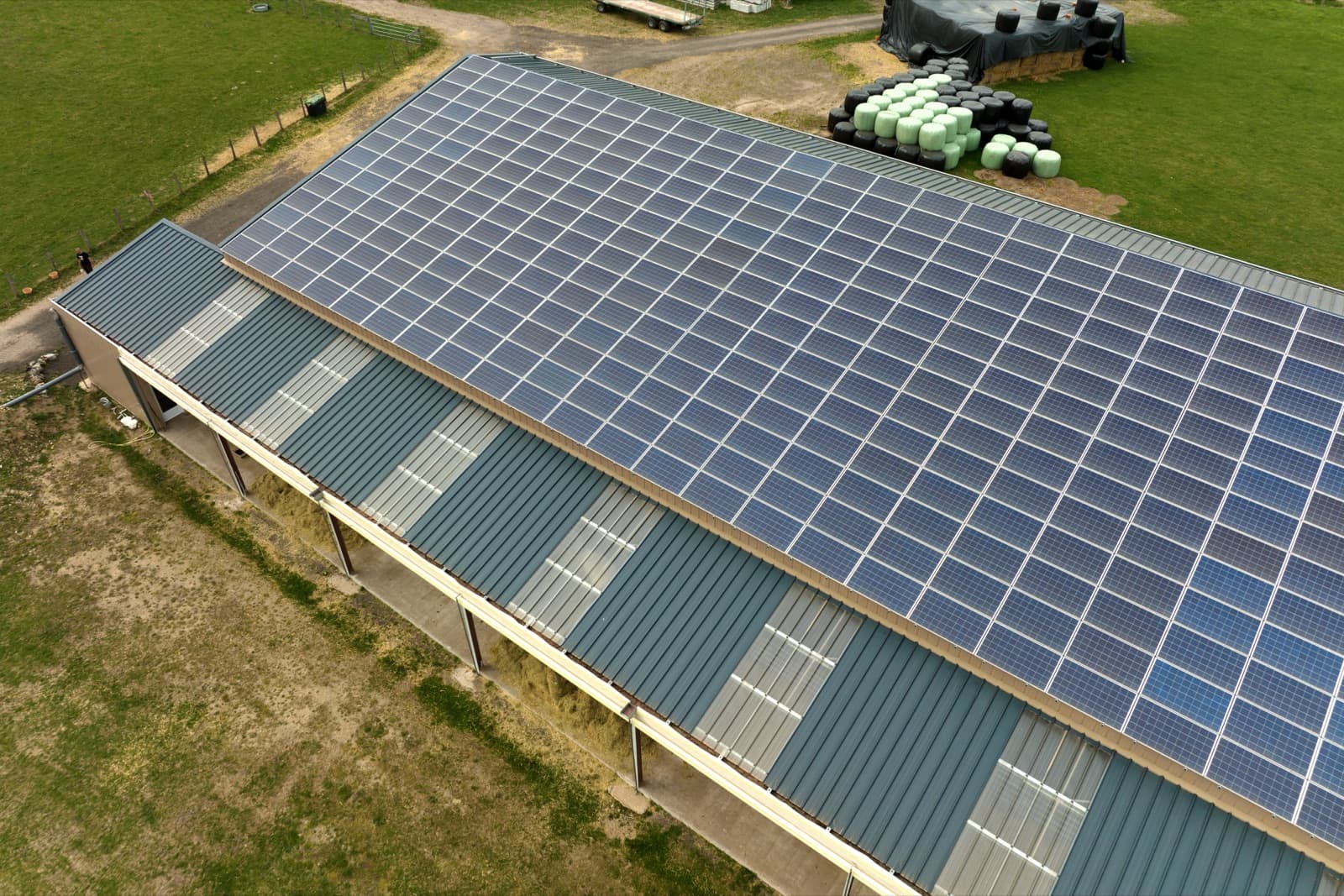 Solar panels covering the roof of a farm building, from above